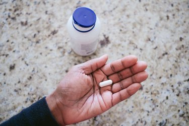 Person holding one of the best magnesium supplements in their palm over the kitchen counter