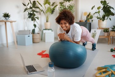 Person doing a plank on an exercise ball at home in living room.