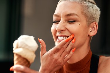 a woman eating an ice cream cone and having tooth pain from tooth sensitivity to cold