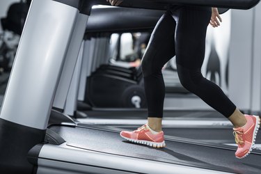 Close-up image of person's legs walking on a treadmill set to an incline.
