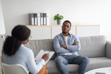 a person sitting on a grey couch talking to a therapist